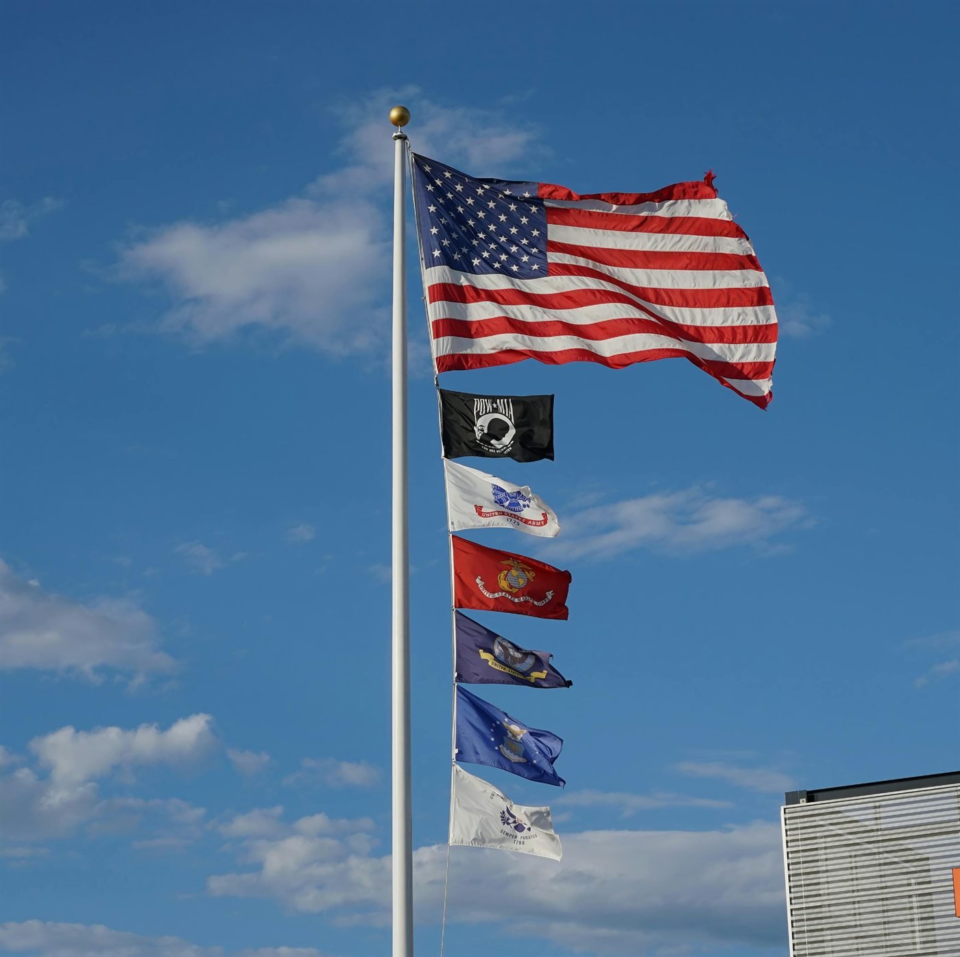 American flag flying beside military service flags